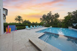 A swimming pool with lounge chairs and a basketball hoop, surrounded by greenery and a sunset sky. - Glamorous Getaway With Themed Bedrooms at Reunion (Kissimmee)