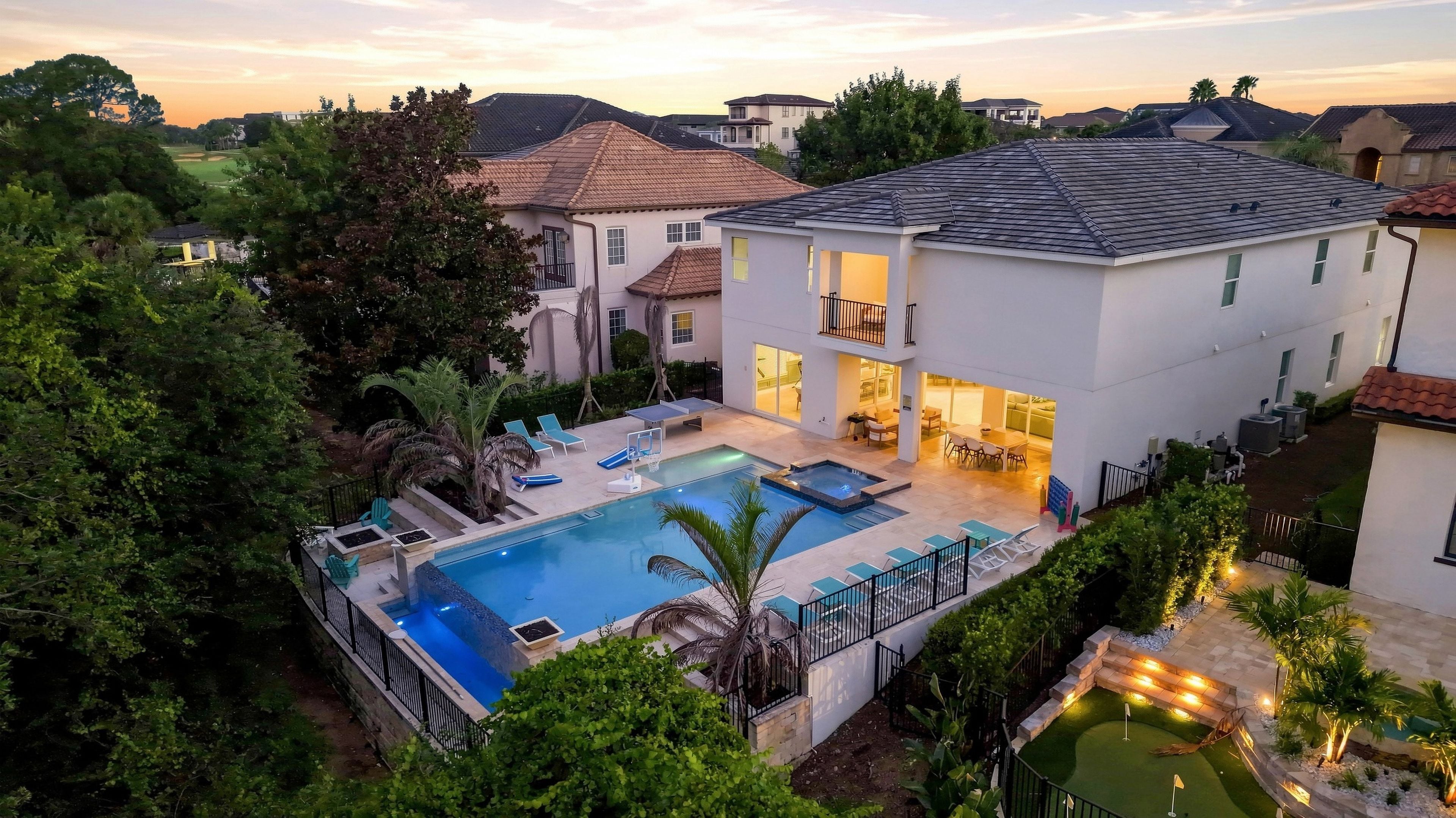 A two-story house with a swimming pool, outdoor seating, and a golf course in the background.