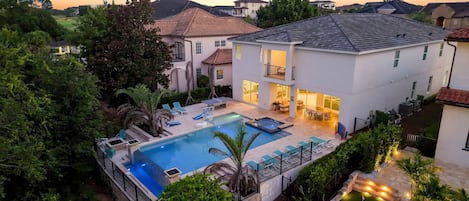 A two-story house with a swimming pool, outdoor seating, and a golf course in the background.