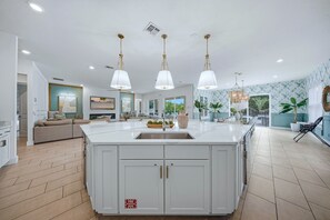 A spacious kitchen with a large island, white cabinetry, and pendant lighting. - Glamorous Getaway With Themed Bedrooms at Reunion (Kissimmee)