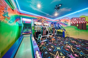 A colorful arcade with racing games, a claw machine, and a 'NITQUES' sign. - Glamorous Getaway With Themed Bedrooms at Reunion (Kissimmee)