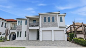 A modern two-story house with a stone facade, a balcony with outdoor furniture, and a garage. - Glamorous Getaway With Themed Bedrooms at Reunion (Kissimmee)