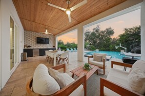 A spacious patio with a pool, wooden ceiling, and a dining area. - Glamorous Getaway With Themed Bedrooms at Reunion (Kissimmee)