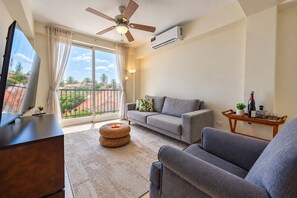 A living room with a sofa, armchair, TV, and a balcony with a view. - Hard Rock Central Suite,  Balcony, Parking (San Felipe de Puerto Plta)
