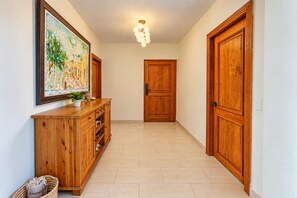 A hallway with wooden doors, a wooden cabinet with drawers, a hanging painting, and a ceiling light fixture. - Hard Rock Central Suite,  Balcony, Parking (San Felipe de Puerto Plta)