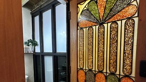 Ein Badezimmer mit Toilette, einem Fenster und einer Tür mit dekorativer Glasverkleidung.