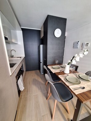 A modern kitchen with a dining area, a clock on the wall, and a vase with flowers on the table. - Borde Vivo Santiago by Domus Travels (Santiago)