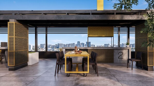 A modern outdoor dining area with a city view, featuring a table and chairs, a hanging light fixture, and a number '2' on the wall. - Borde Vivo Santiago by Domus Travels (Santiago)