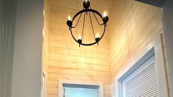 A hallway with wooden walls and a polished floor leading to a bathroom with a sink and mirror.