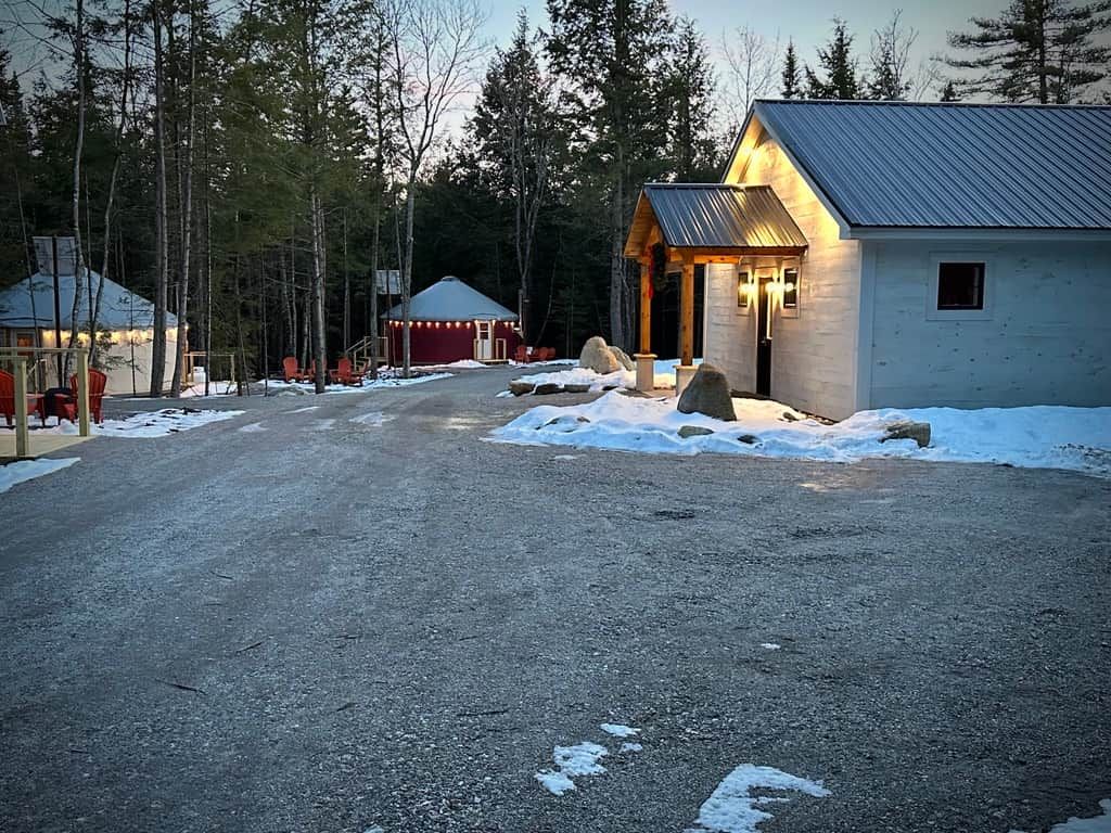 En stuga med ett tak av metall, en inglasad veranda och en snötäckt mark.