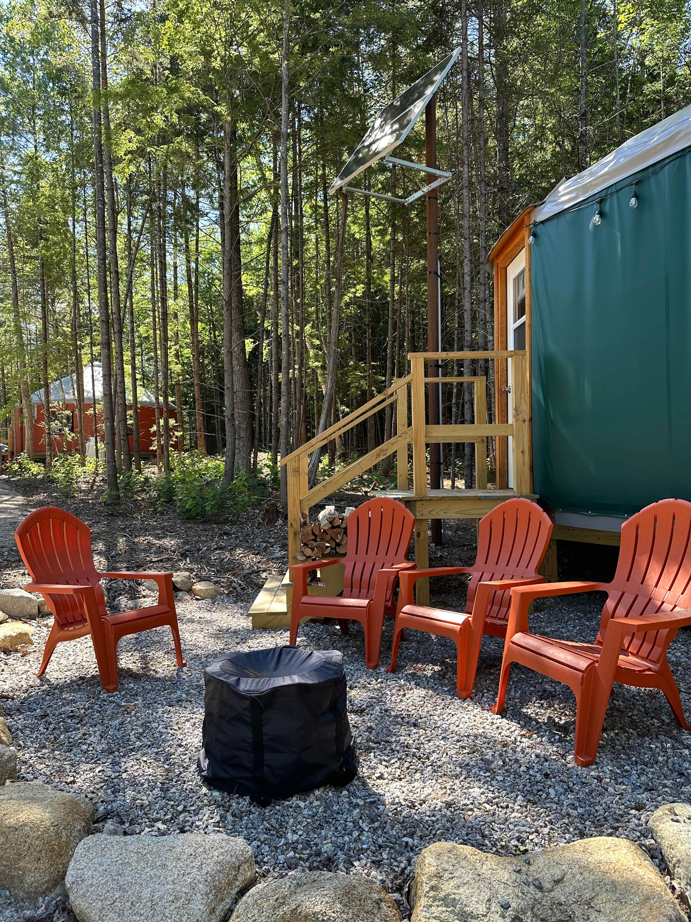 Eine Holzhütte mit einer Holzterrasse, Sitzgelegenheiten im Freien und einer Feuerstelle.