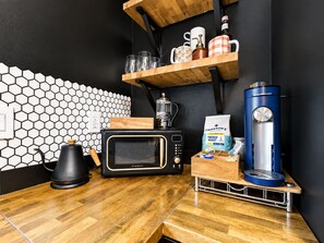 A kitchen with a microwave, coffee maker, and a coffee grinder on the counter.