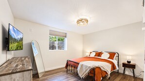 Quarto com cama, escrivaninha, televisão e janela.