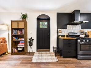 A modern kitchen with a black stove, wooden cabinets, and a black door.