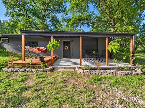 A modern house with a covered patio, a hammock, and a door leading to a garage.