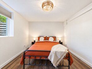 A bedroom with a bed, bedside lamps, a window, and a ceiling light fixture.
