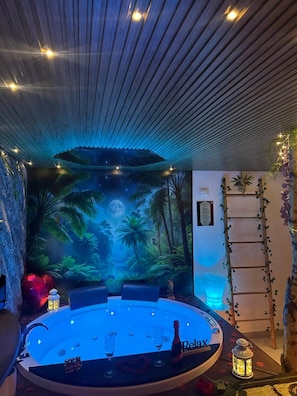 Una stanza con un tavolo rotondo, un affresco con una scena tropicale e una scala appoggiata al muro.