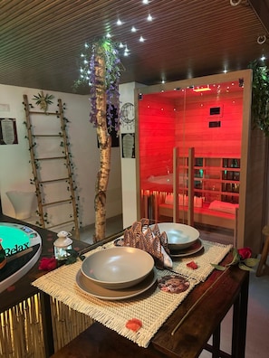 Una stanza con soffitto in legno, una poltrona massaggiante, un lettino da massaggio e illuminazione rossa.