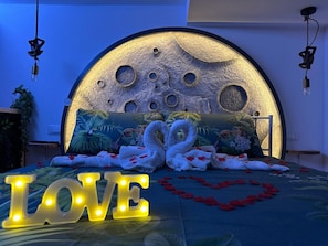 Un letto con una testiera a tema lunare, due cigni e un cartello con la scritta 'LOVE'.