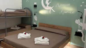 A bedroom with a bunk bed, a single bed, a wall decal of a moon and stars, and neatly folded towels with a rose. - 'Moonlight Jungle' Apartment with Balcony, Wi-Fi and Air Conditioning (Avola)