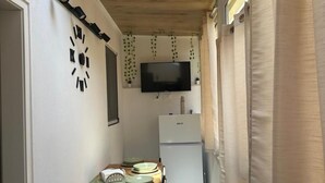 A compact kitchen with a wooden ceiling, a flat-screen TV, a refrigerator, and a dining table with plates. - 'Moonlight Jungle' Apartment with Balcony, Wi-Fi and Air Conditioning (Avola)