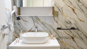 A bathroom with a marble backsplash, a white vanity with a sink, a mirror above the vanity, and a black stool. - 'Moonlight Jungle' Apartment with Balcony, Wi-Fi and Air Conditioning (Avola)