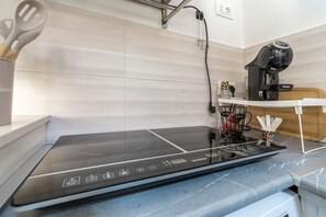 A modern kitchen with a built-in induction cooktop, a coffee machine, and a coffee station. - 'Moonlight Jungle' Apartment with Balcony, Wi-Fi and Air Conditioning (Avola)