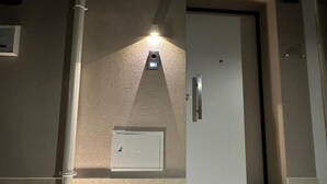 A hotel entrance with a door, a light fixture above it, and a small air conditioning unit on the wall. - 'Moonlight Jungle' Apartment with Balcony, Wi-Fi and Air Conditioning (Avola)