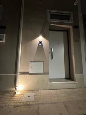L'ingresso di un hotel con una porta, un lampadario sopra e un piccolo condizionatore d'aria sulla parete.
