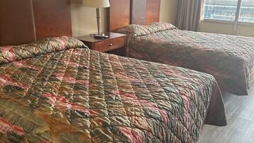A hotel room with two beds, a nightstand with a lamp, and framed pictures on the wall.