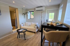 A compact living space with a sofa, a small round table, a dining table, and a chair. - Morgensolen - Free Parking & Mountain Trails (bones)
