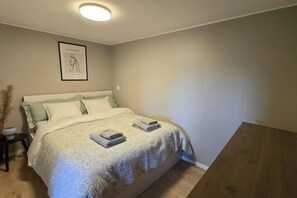 A bedroom with a bed, a bedside table, a framed picture on the wall, and a small potted plant. - Morgensolen - Free Parking & Mountain Trails (bones)