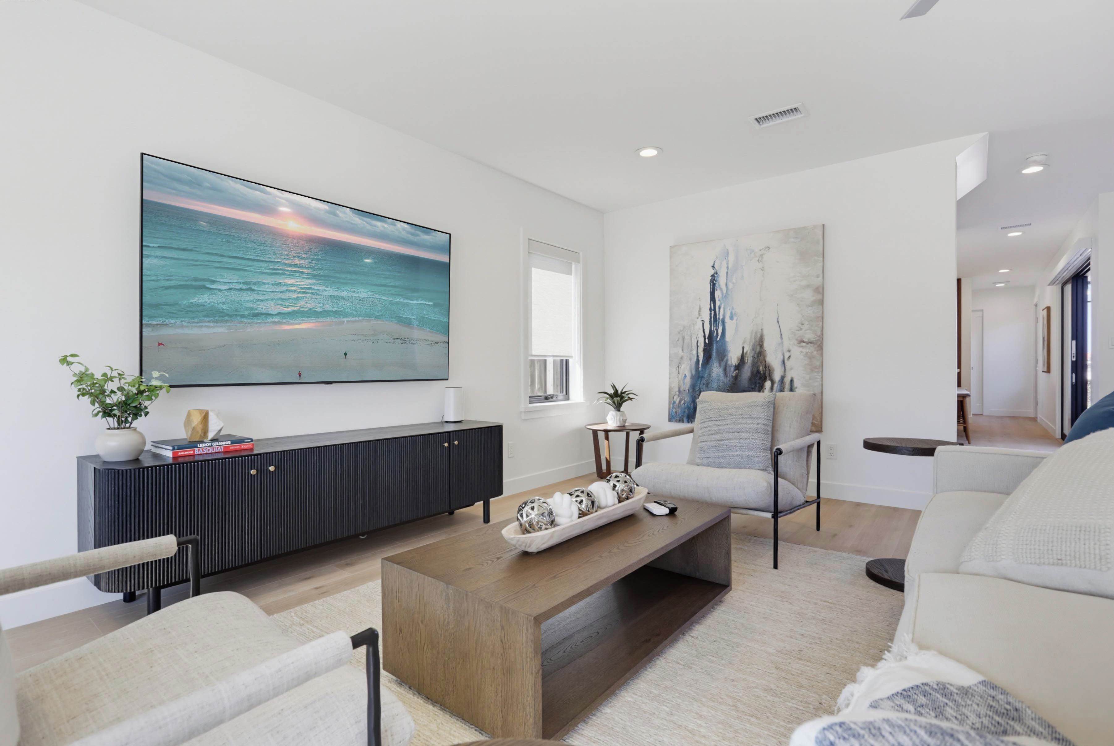 A modern living room with a large flat-screen TV, a wooden coffee table, and a comfortable seating area.