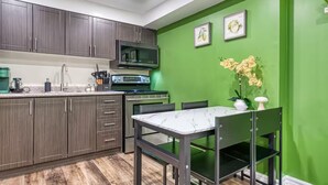 Una cocina con armarios de madera oscura, un refrigerador de acero inoxidable y un comedor con sillas.