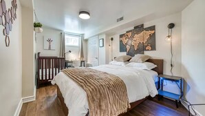 Un dormitorio con una cama grande, un escritorio, una silla, una planta colgante y un mapa mundial en la pared.