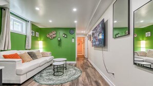 Una sala de estar con un sofá blanco, una mesa de centro redonda y una pared verde.