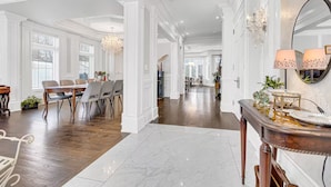 Um quarto espaçoso com área de jantar, um espelho grande e um candelabro.