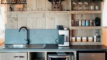 Eine kompakte Küche mit integrierter Kaffeemaschine, Toaster und Kühlschrank.