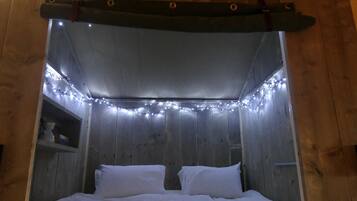 A bed with white bedding, a wooden headboard, and string lights.
