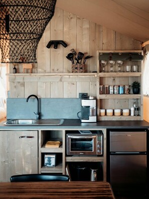 A compact kitchen with a built-in coffee maker, a toaster, and a refrigerator.