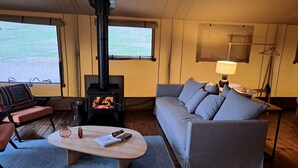 Ein gemütliches Wohnzimmer mit einer Couch, einem Couchtisch, einem Kamin und Blick durch große Fenster.