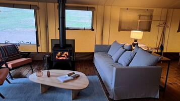 Ein gemütliches Wohnzimmer mit einer Couch, einem Couchtisch, einem Kamin und Blick durch große Fenster.