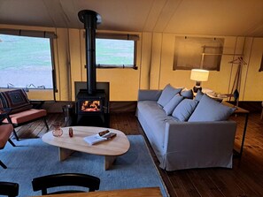 Ein gemütliches Wohnzimmer mit einer Couch, einem Couchtisch, einem Kamin und Blick durch große Fenster.