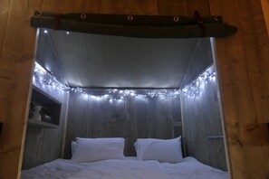 A bed with white bedding, a wooden headboard, and string lights.
