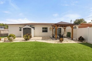 A single-story house with a covered patio, a garage, and a well-maintained lawn. - Spacious Home + Private Studio | Close to Beach (Kenneth City)