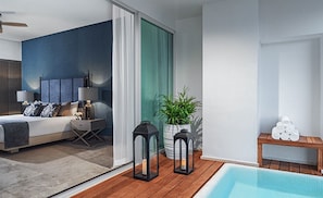 Ett modernt sovrum med en stor säng, sänglampor och utsikt över en swimmingpool.
