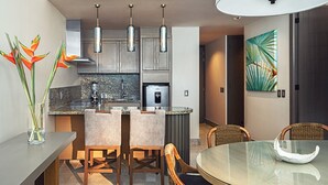 A modern kitchen with a central island, pendant lighting, and a dining area with a glass table and chairs. - Exclusive Grand Mayan 1BR Suite w/ Plunge Pool Oct 26 - Nov 2 Confirmed (Nuevo Nayarit)