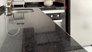 Una cocina moderna con encimera negra, electrodomésticos de acero inoxidable y muebles de madera.