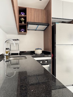 A modern kitchen with a black countertop, stainless steel appliances, and wooden cabinetry. - Fabulous 1-bedroom studio perfect for a relaxing getaway (Unknown)