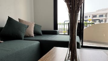 Una stanza con un divano verde, un tavolo in legno e un vaso con fiori secchi.